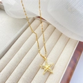 Détail d'un pendentif étoile doré avec cristaux micro-pavés sur fond de tissu blanc doux - Étoile à cinq branches-Or