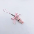 Vue détaillée d'un charm lapin rose floqué avec un nœud satiné et du matériel en métal - Lapin rose