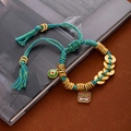 Macro detail of braided cord bracelet with gold coins and lion enamel charm - L403 Five Emperor Coins Green