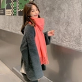 Pink orange cashmere-feel scarf with tassels worn by model against a concrete wall - Watermelon red