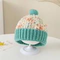 Detail van de meerkleurige gebreide muts met groene pompon en getextureerd garen - Eén maat / Meerblauw