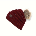 Close-up of a burgundy confetti knit beanie with a fluffy brown faux fur pom-pom - Burgundy