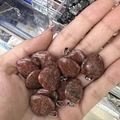 Natural reddish-brown heart-shaped stone pendants held in hand for jewelry making - Red Sesame Stone