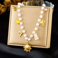 Détail de breloques dorées cœur et cerise sur un collier de perles blanches et chaîne or - Style Portrait Pièce Coeur Dauphin Cerise (N3430)