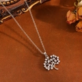 Close-up of silver Tree of Life necklace with clear stones on a vintage brown fabric background - Silver White Zircon Tree Necklace (T031)