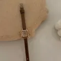 Dettaglio dell'orologio al quarzo quadrato oro rosa con cinturino in pelle marrone - caffè