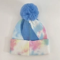 Close-up of tie-dye knit beanie featuring a large blue faux fur pompom and ribbed texture - Pale Blue