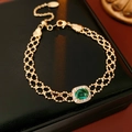 Detail van een vintage gouden armband met groene ovale edelsteen en micro-pave kristallen - Armband - Goud / Goud