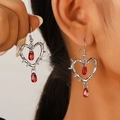 Macro detail of gothic thorn heart earrings with red crystal teardrops on a model - Red Water Drop Barbed Heart (N-300)