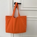 Detail of a bright orange canvas tote bag hanging on a white door handle - Solid Orange
