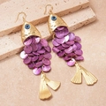 Detail view of gold fish-shaped earrings with purple scales and blue evil eye detail - Purple