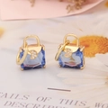 Detailed close-up of blue gemstone handbag earrings with a gold moon and zircon accent - Sapphire Blue