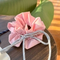 Detailansicht der rosa Stoffbeuteltasche mit Wellenkante und dicker grauer Kordel auf Holz - Erdbeerrosa Schleife Kordelzug Scrunchie