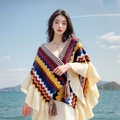 Poncho in maglia bohémien con strisce geometriche colorate e frange indossato in riva al mare - Marrone Giallastro
