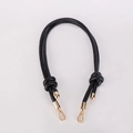 Detail of black leather bag strap with decorative knots and golden metal clasps - Black