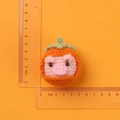 Handmade knit pig pendant wearing orange persimmon hat with scale for size measurement - Pink Pig with Persimmon Hat