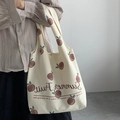 Off-white canvas tote bag with red fruit print shown in a stylish over-the-shoulder view - Beige Fruit