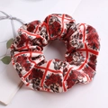 Detail of satin scrunchie featuring vintage red roses and skull prints on cream fabric - Checkered Rose