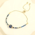 Detail eines verstellbaren Goldketten-Armbands mit blauen Perlen auf einer Schale - Sodalith Stil Armband (SET0340)