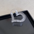 Transparent heart hair claw clip with golden metal spring on a black tray - Heart Shape / Heart Transparent