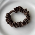 Macro detail of dark brown satin scrunchie with silk luster and accordion pleat texture - Brown