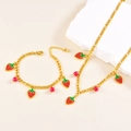 Detailed macro view of gold strawberry necklace and bracelet set with red beads - Necklace + Bracelet