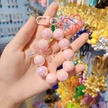 Pink iridescent beaded keychain featuring a transparent bow and animal charm accessory - Pink