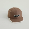 Detail van bruine katoenen baseballpet met Nice borduursel en witte bies aan de rand - koffiekleur