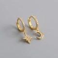 Primer plano de pendientes asimétricos de oro con estrellas, lunas y circonitas - Dorado
