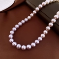 Macro detail of high-gloss lavender freshwater pearl necklace on a brown satin background - 10mm / Purple