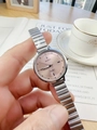 Detail of silver chain watch with pink dial held against a cozy coffee and book background - Pink