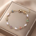Detail of a gold bracelet with colorful enamel butterflies and baroque pearls on silk - Butterfly Oval Pearl Bracelet