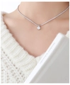 Detail of silver tennis chain necklace with a round solitaire pendant on a model - Silver