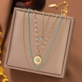 Detail of layered gold necklace with sunburst pendant and turquoise beads set on jewelry box - Round Turquoise Disc Necklace - Gold