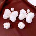 Detail view of pearl bow earrings with plush pompom on dark velvet surface - White (Silver Needle Bow Pom Pom)