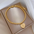 Detail of golden bead chain bracelet with a heart coin pendant featuring a portrait - Gold (K533)
