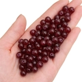 Deep red round glass beads for DIY jewelry held in hand showing texture and gloss - Garnet Red approx 50pcs/pack
