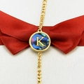 Golden bracelet with round abalone shell pendant featuring an inlaid letter K design - Letter K
