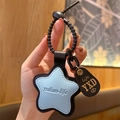 Star-shaped light blue leather keychain with brown charm and black spiral cord strap - Leather-Blue Star