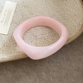 Close-up of a wide pink translucent resin bangle with irregular geometric design on a tray - Light Pink