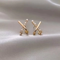 Macro shot of gold crisscross X earrings featuring white pearls and zircon on silk background - Cross Personality Earrings - E5601 Gold