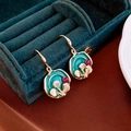 Macro shot of vintage gold drop earrings with blue enamel, pearl flowers and red crystals - Green Enamel Pearl Crystal Hooks