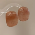 Macro shot of irregular oval resin earrings with orange mineral texture and top holes - Brown
