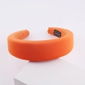 Vibrant orange milk silk sponge headband with handmade tag on a minimalist stand - Orange