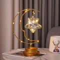 Close-up of golden iron crescent moon and star LED night light on marble tabletop - Smiling Moon Lamp - Plastic Star / Battery-Warm Light