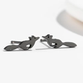 Vista macro de pendientes de zorro negro con un acabado metálico minimalista y brillante - Negro