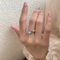 Silver bow ring with pear-cut light blue stone and pave crystals worn on finger - Butterfly Blue Gem