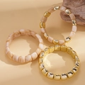 Detail von dreiteiligem Stretch-Armband-Set mit Goldmetall und Marmor-Harzperlen - Gebrochenes Weiß