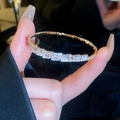Macro shot of gold bracelet with sparkling emerald-cut cubic zirconia in dark setting - Gold