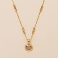 Close-up of gold layered necklace featuring a round natural stone pendant on beige background - Moonstone